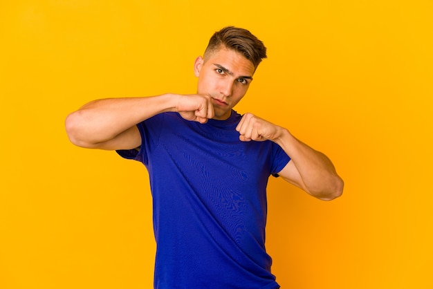 Young handsome caucasian man isolated throwing a punch, anger, fighting due to an argument, boxing.