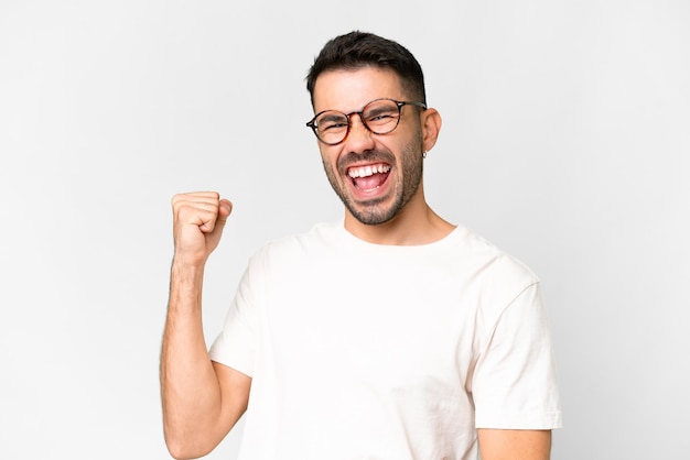 Young handsome caucasian man over isolated white background celebrating a victory