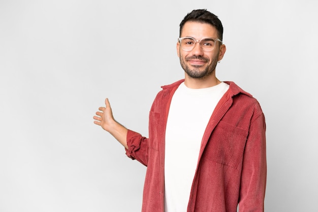 Young handsome caucasian man over isolated white background extending hands to the side for inviting to come