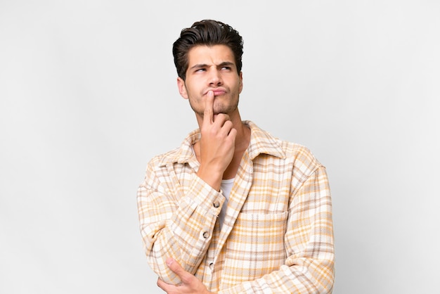 Young handsome caucasian man over isolated white background having doubts while looking up