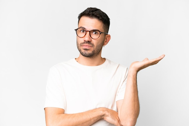 Young handsome caucasian man over isolated white background having doubts