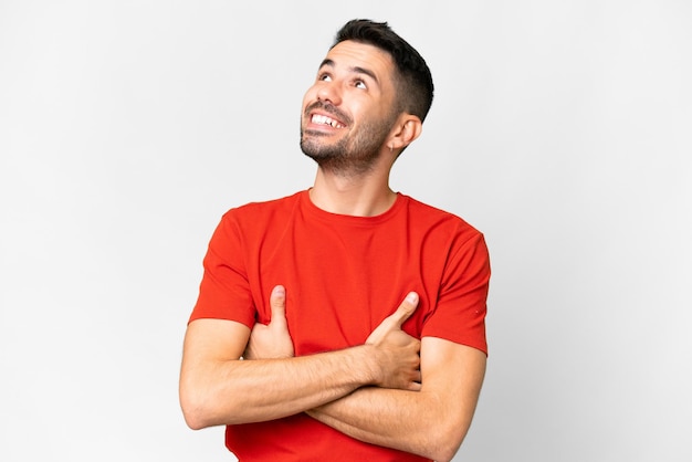 Young handsome caucasian man over isolated white background looking up while smiling