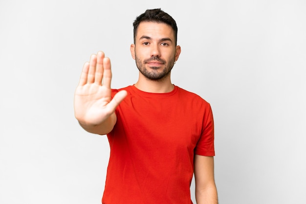 Young handsome caucasian man over isolated white background making stop gesture