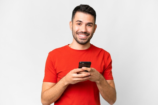 Young handsome caucasian man over isolated white background sending a message with the mobile