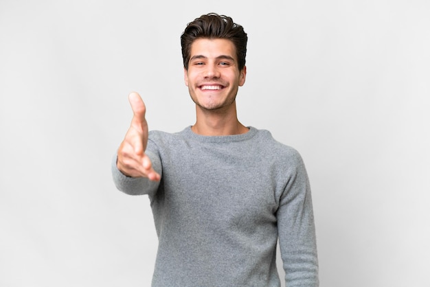 Young handsome caucasian man over isolated white background shaking hands for closing a good deal