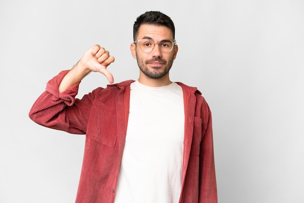 Young handsome caucasian man over isolated white background showing thumb down with negative expression