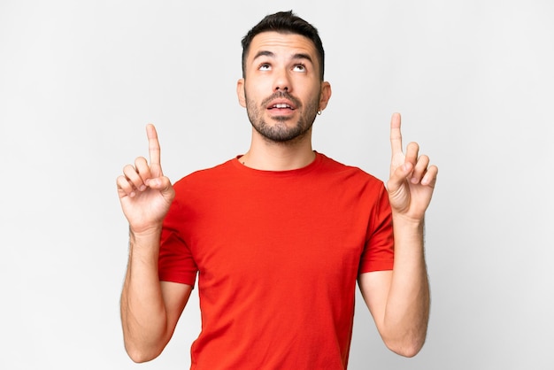 Young handsome caucasian man over isolated white background surprised and pointing up