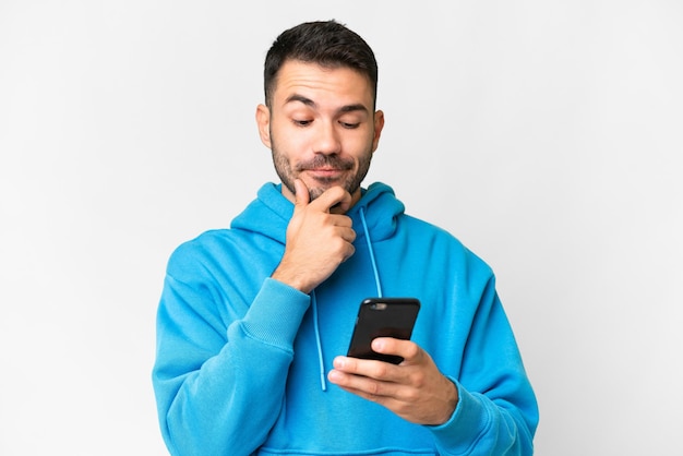 Young handsome caucasian man over isolated white background thinking and sending a message