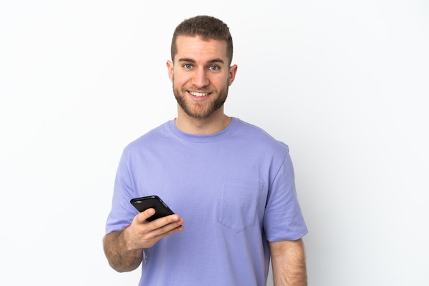 Young handsome caucasian man isolated on white background using mobile phone