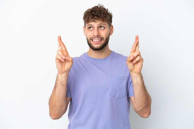 Young handsome caucasian man isolated on white background with fingers crossing and wishing the best