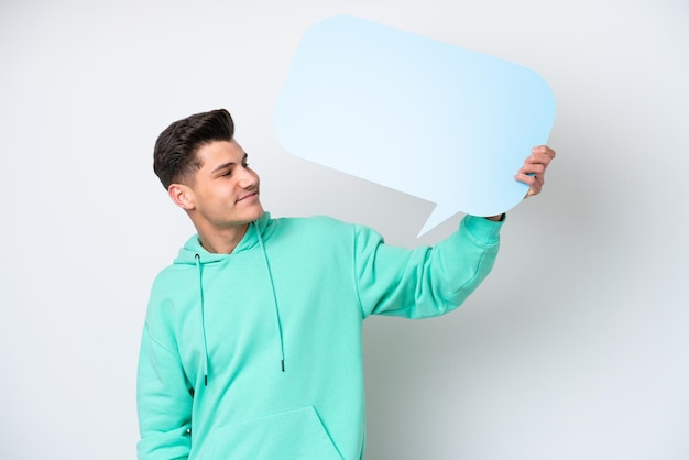 Photo young handsome caucasian man isolated on white bakcground holding an empty speech bubble