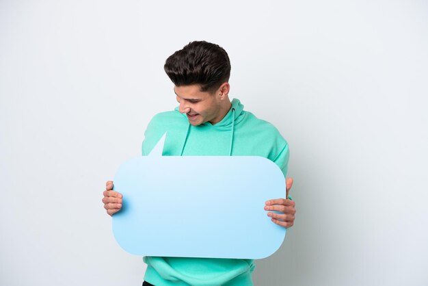 Photo young handsome caucasian man isolated on white bakcground holding an empty speech bubble