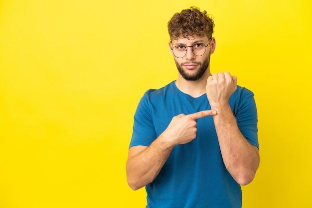 Young handsome caucasian man isolated on yellow background making the gesture of being late