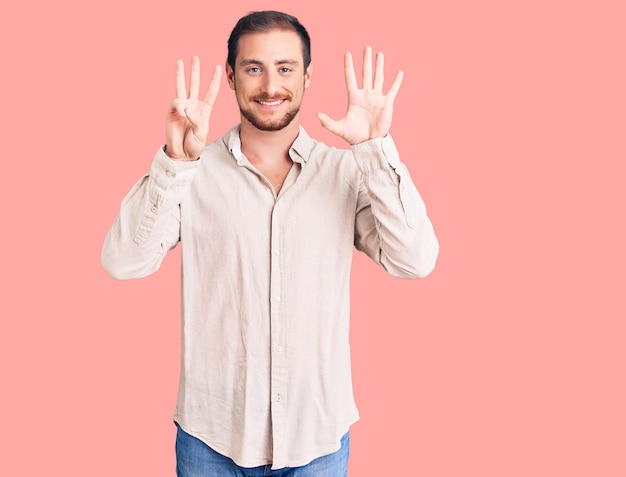 Young handsome caucasian man wearing casual clothes showing and pointing up with fingers number eight while smiling confident and happy.