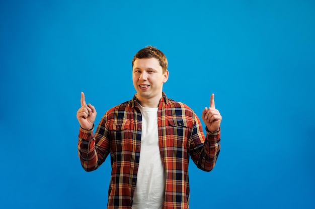 Young handsome european man in casual shirt point index fingers overhead on workspace area mockup on blue studio background I have an idea