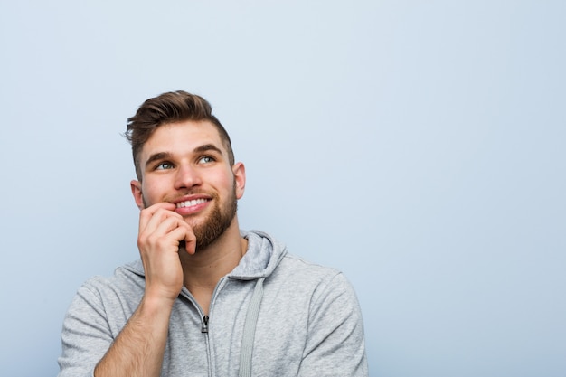 Young handsome fitness man relaxed thinking about something looking a copyspace.