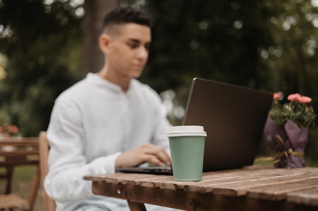 Young handsome freelancer working on laptop remotely. Happy man in a IT park, doing his work from distance.