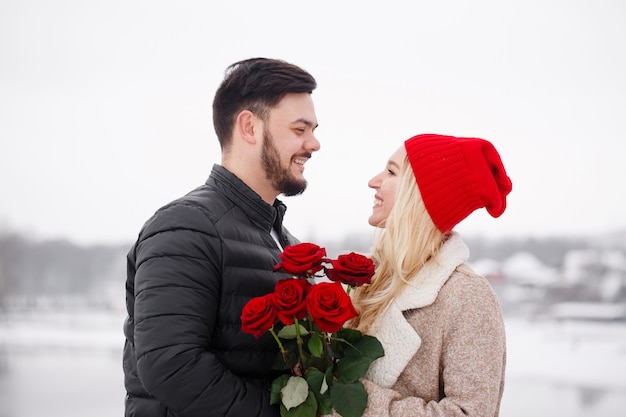 Young handsome guy giving a woman a bouquet of roses on valentine's day