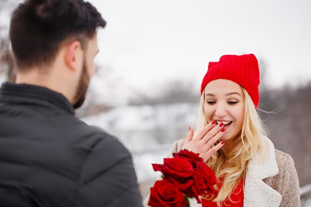 Young handsome guy giving a woman a bouquet of roses on valentine's day