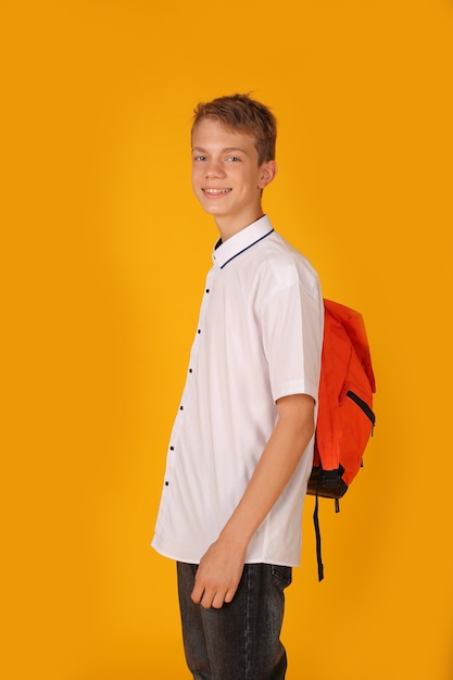 a young handsome guy in a white shirt with an orange backpack on his shoulders yellow background