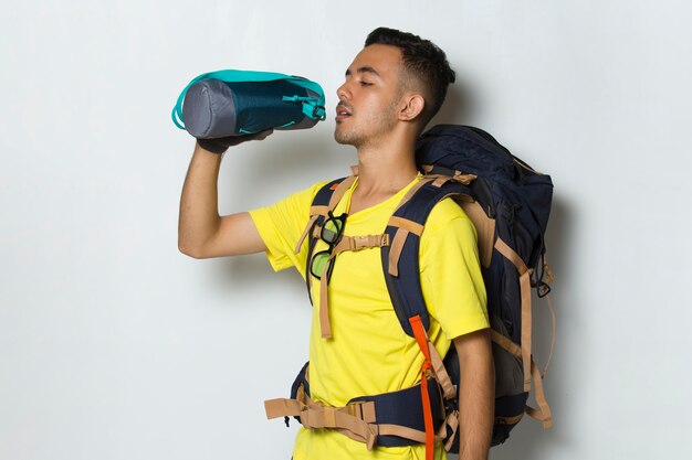 Young handsome hiker man drinking water on white background