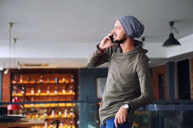 Young handsome hipster man using smartphone in cafe