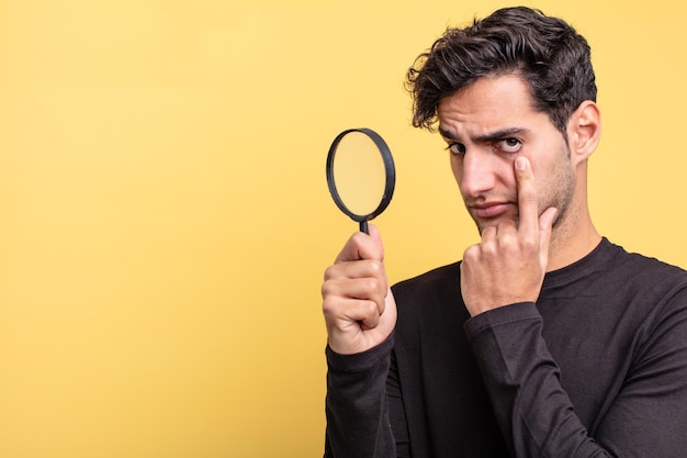 Young handsome hispanic man. magnifying glass concept