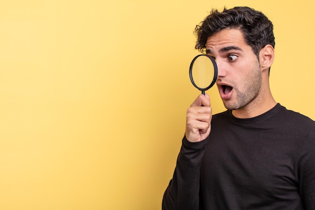 young handsome hispanic man. magnifying glass concept