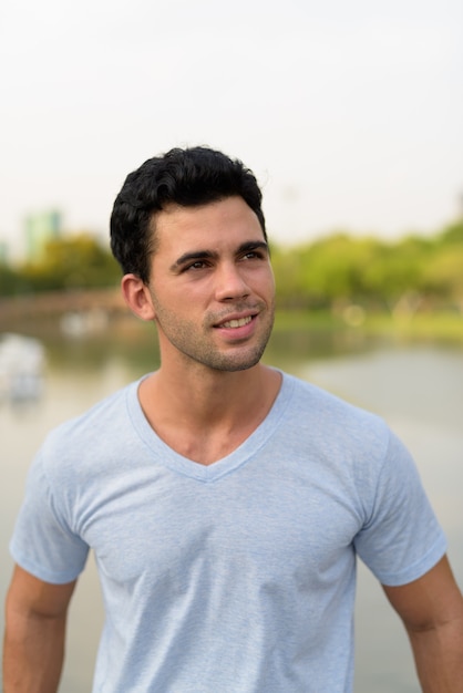 Young handsome Hispanic man relaxing in the park