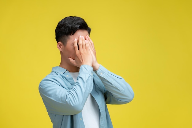 Young handsome holding his head looking desperate isolated on yellow background