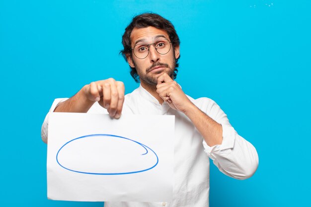 Photo young handsome indian businessman showing a remark sheet of paper