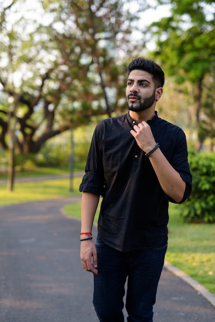 Young handsome Indian man thinking while walking on the road