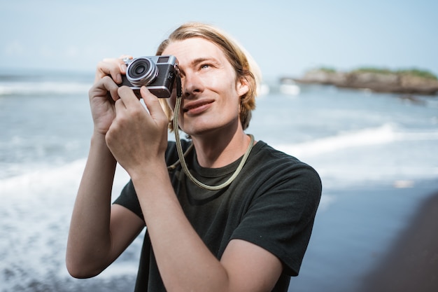 Young handsome male photographer on the beach