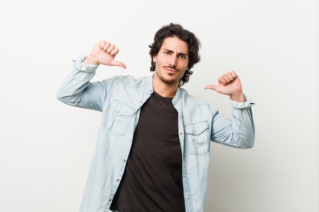 Young handsome man against a white wall feels proud and self confident