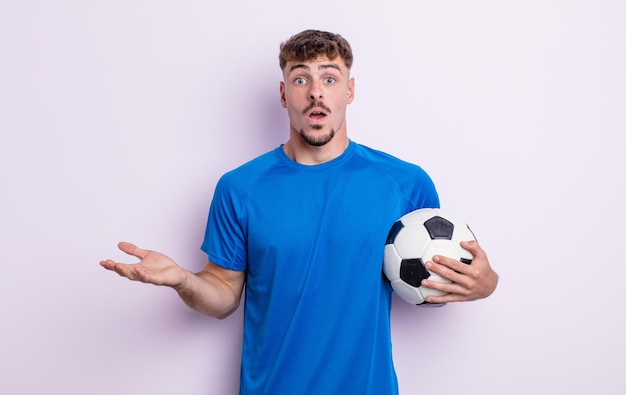 Young handsome man amazed, shocked and astonished with an unbelievable surprise. soccer concept