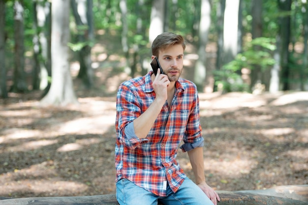 Young handsome man in checkered shirt speak on phone outdoor