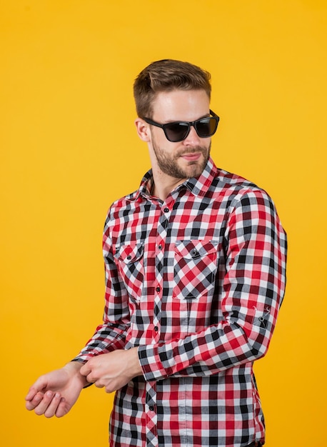 Young handsome man in checkered shirt and sunglasses has bristle on face, casual style.