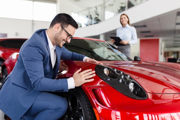 Young handsome man choosing a new car at car showroom.