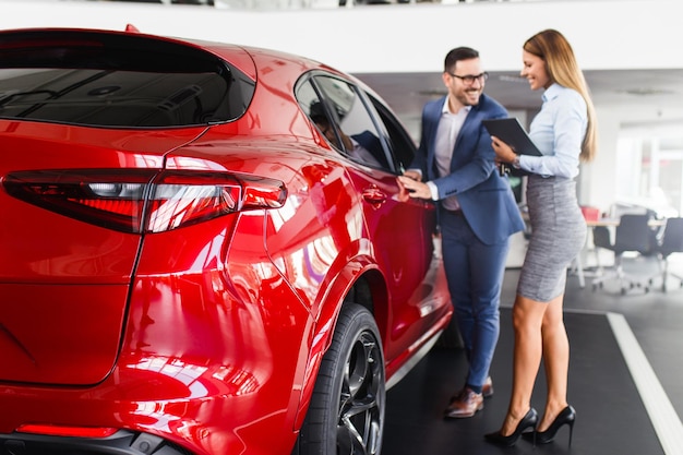 Young handsome man choosing a new car at car showroom.