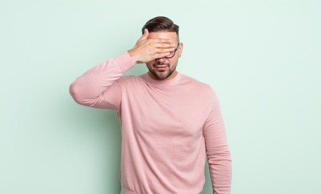 Young handsome man covering eyes with one hand feeling scared or anxious, wondering or blindly waiting for a surprise