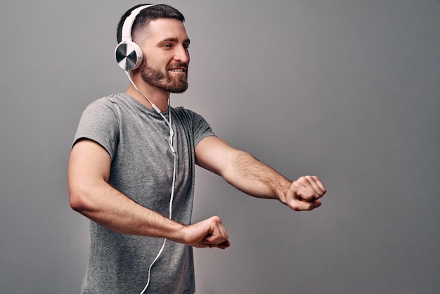 young handsome man dancing to his favorite music track Dressed in a gray Tshirt and white headphones