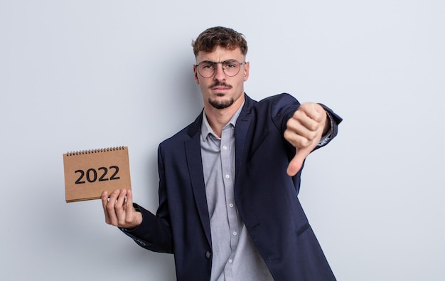 Photo young handsome man feeling cross,showing thumbs down. calendar concept