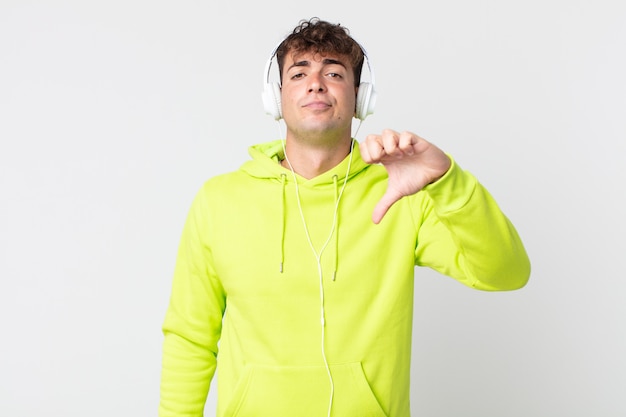 Young handsome man feeling cross,showing thumbs down and headphones