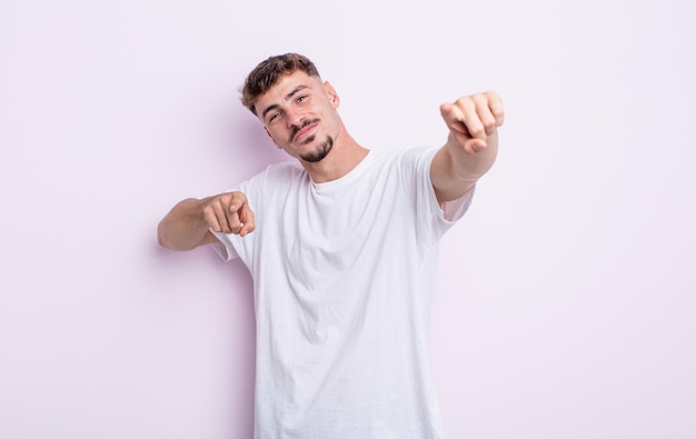 Young handsome man feeling happy and confident pointing to camera with both hands and laughing choosing you