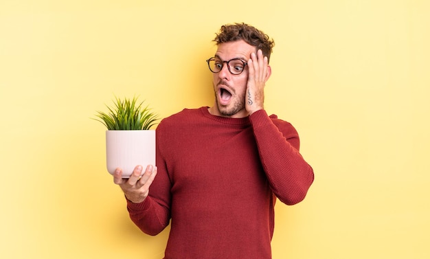 Young handsome man feeling happy, excited and surprised. decorative plant concept