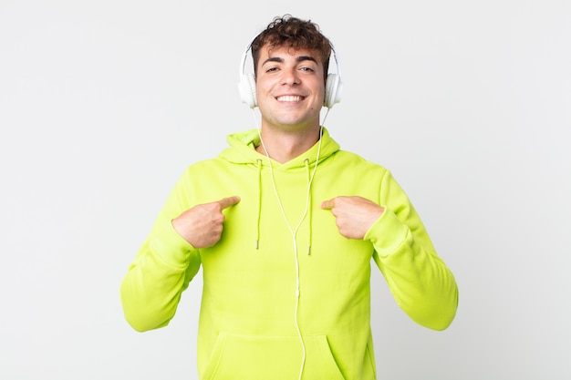 Young handsome man feeling happy and pointing to self with an excited and headphones