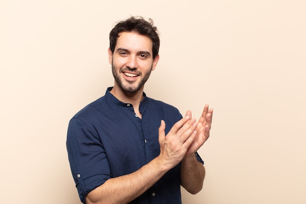 Young handsome man feeling happy and successful, smiling and clapping hands, saying congratulations with an applause