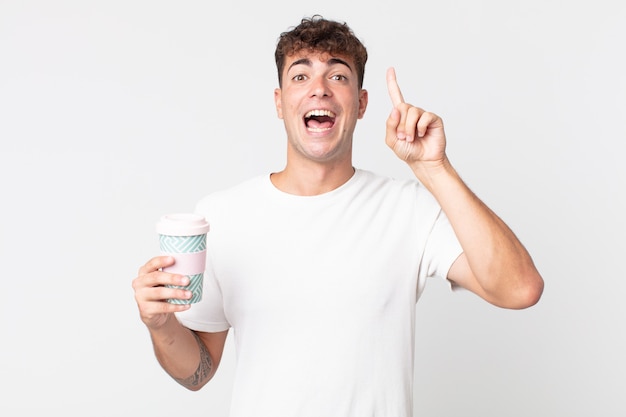 Young handsome man feeling like a happy and excited genius after realizing an idea and holding a take away coffee