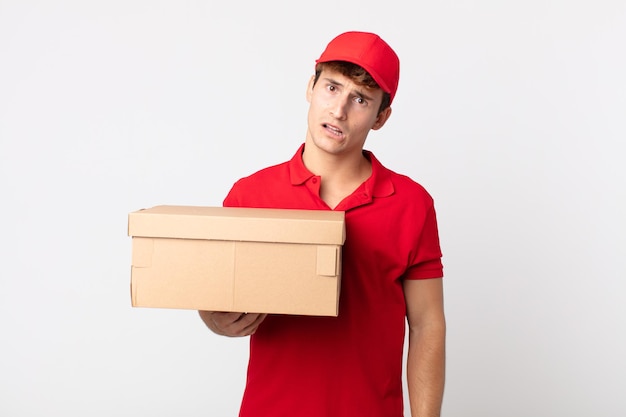 Young handsome man feeling puzzled and confused delivery package service concept