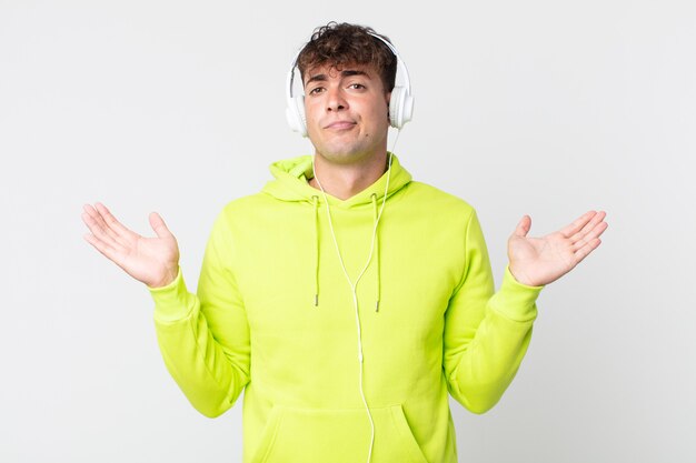 Young handsome man feeling puzzled and confused and doubting and headphones